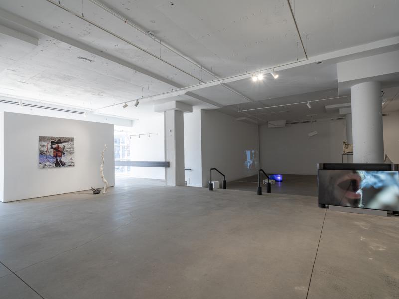 installation image of multiple sculptures, a floor monitor, and projections