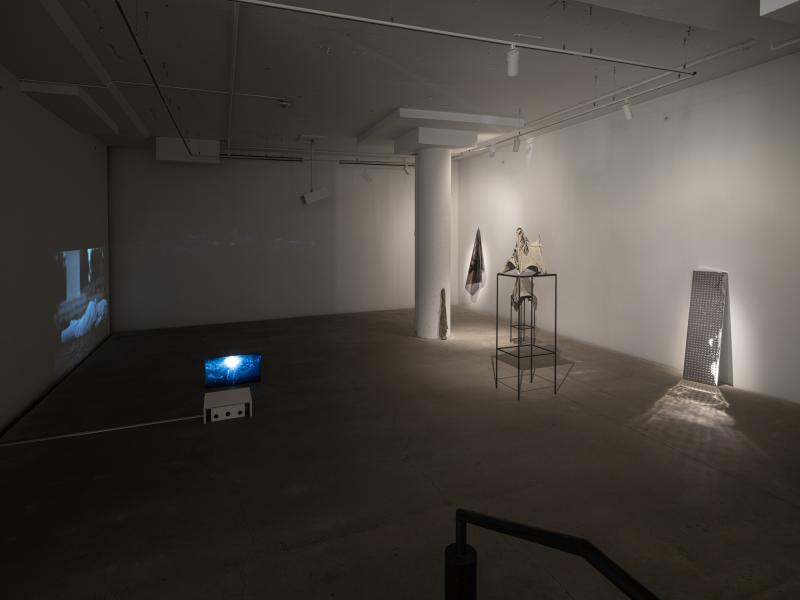 installation image of multiple sculptures and video projections in a dark space