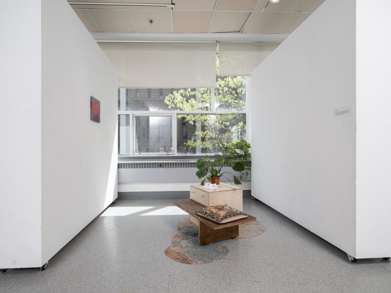 a painting, furniture, and a plant installed in a gallery