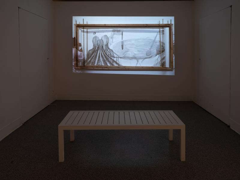 installation image of a projection in front of a gallery bench