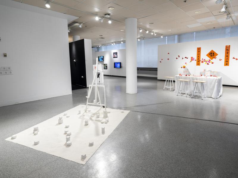 installation image of multiple floor sculptures, wall pieces, and video monitors