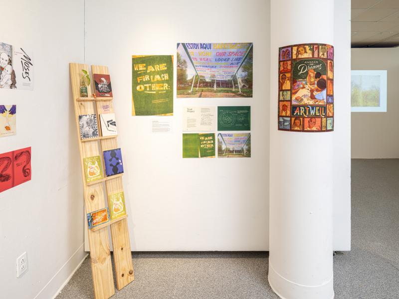 books displayed on a wooden stand and posters installed on gallery walls
