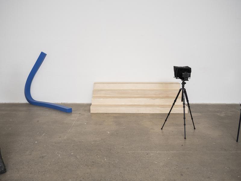 blue latex floor sculpture to the left with wooden stairs and teleprompter to the right