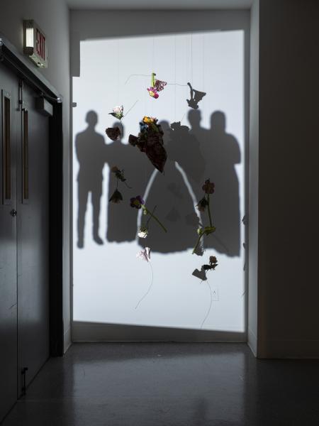 hanging flowers in front of a projected image on the gallery wall 