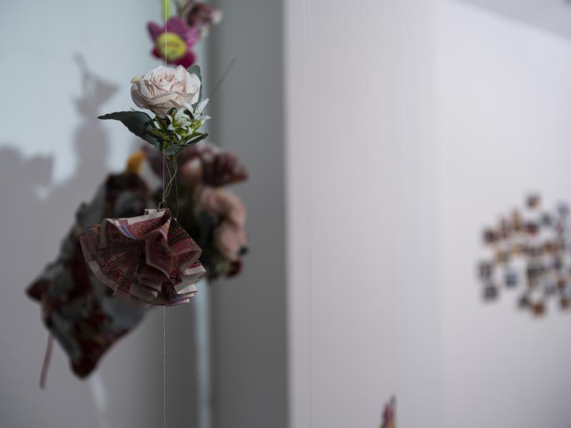 hanging flowers in front of a projected image on the gallery wall 