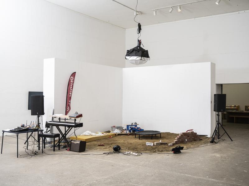 installation image with audio equipment, and props positioned on a bed of sand