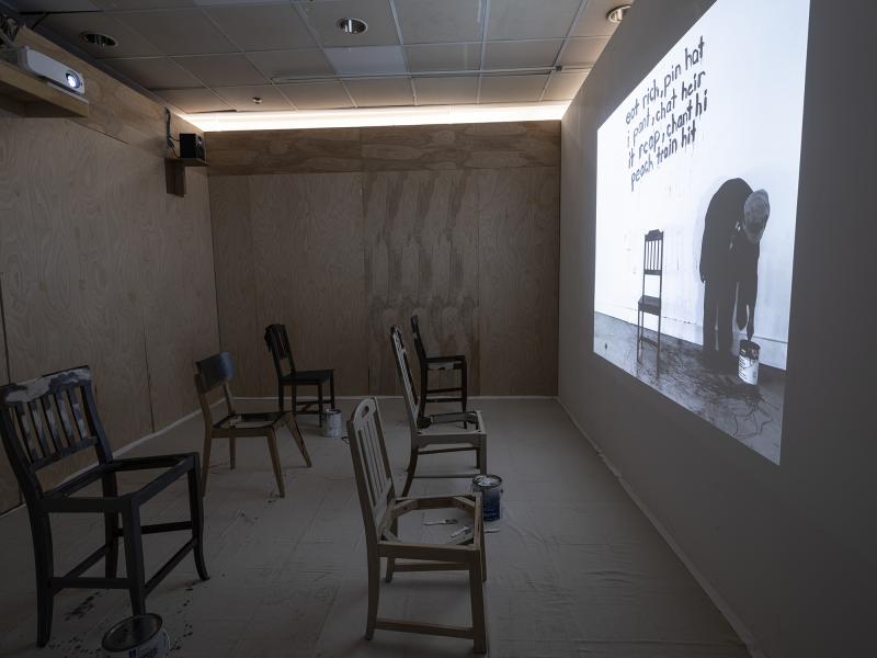 video projection with several painted chairs installation