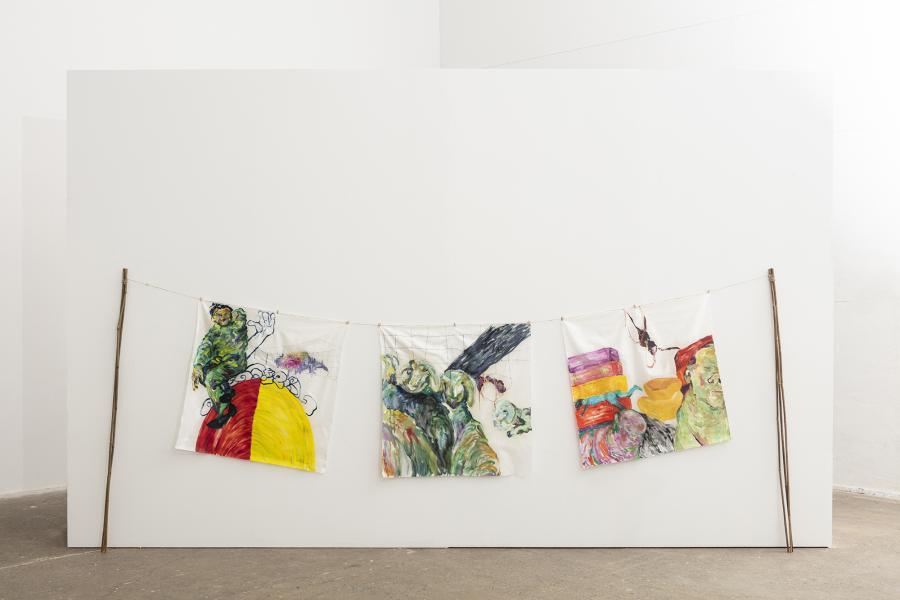 Image of three paintings on silk suspended on a thin rope between bamboo poles