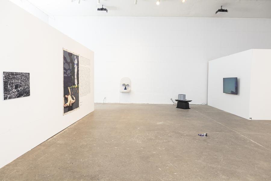 installation image of photography, painting, wall hung fountain, video pieces and a small floor sculpture