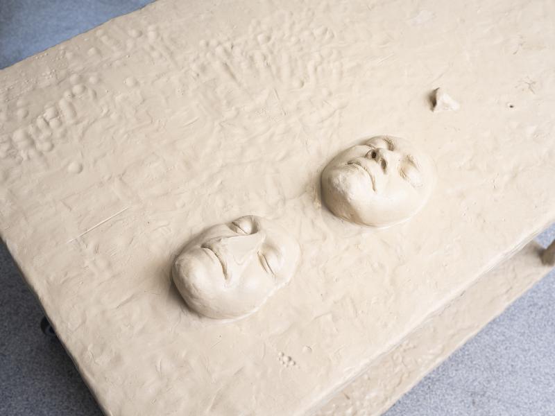 detail of carved faces on a sculpture's surface