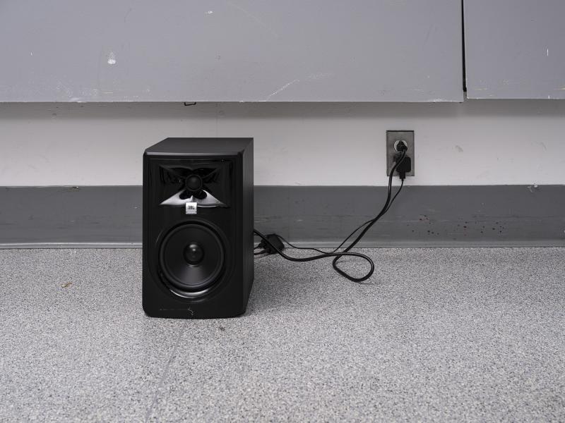 image of a small speaker installed on the floor of a gallery