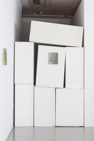 paintings installed on a stack of pedestals and a gallery wall