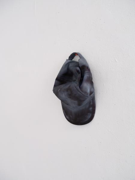 installation image of a sculpture installed on a wall using a brimmed hat