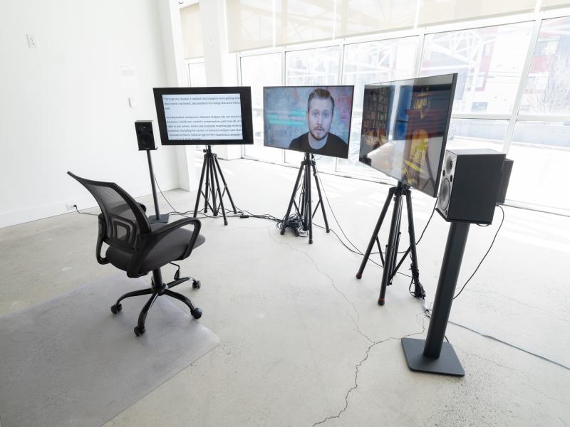 video installation with three monitors on stands and a rolling chair