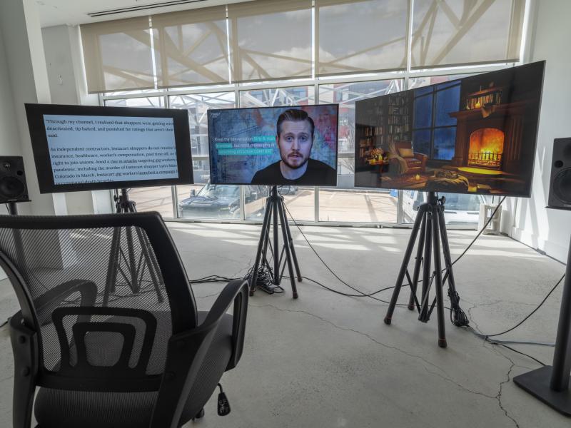 video installation with three monitors on stands and a rolling chair