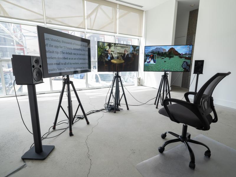 video installation with three monitors on stands and a rolling chair