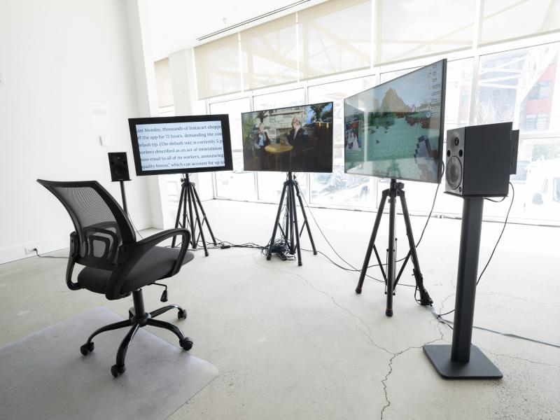 video installation with three monitors on stands and a rolling chair