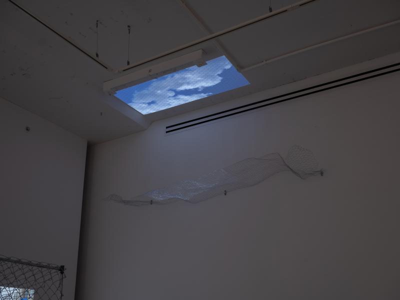 installation image of a ceiling projection through a wall mounted sculpture