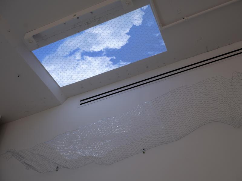 installation image of a ceiling projection through a wall mounted sculpture