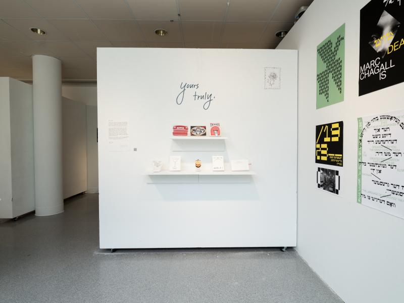 installation image of multiple graphics, vinyl, and objects on a shelf, installed on a wall