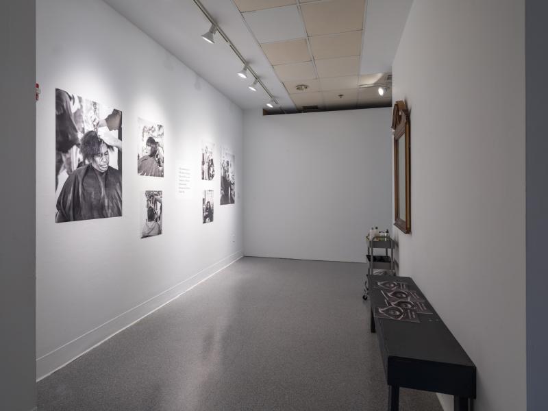 installation image of multiple photographs installed on a wall and a seating area