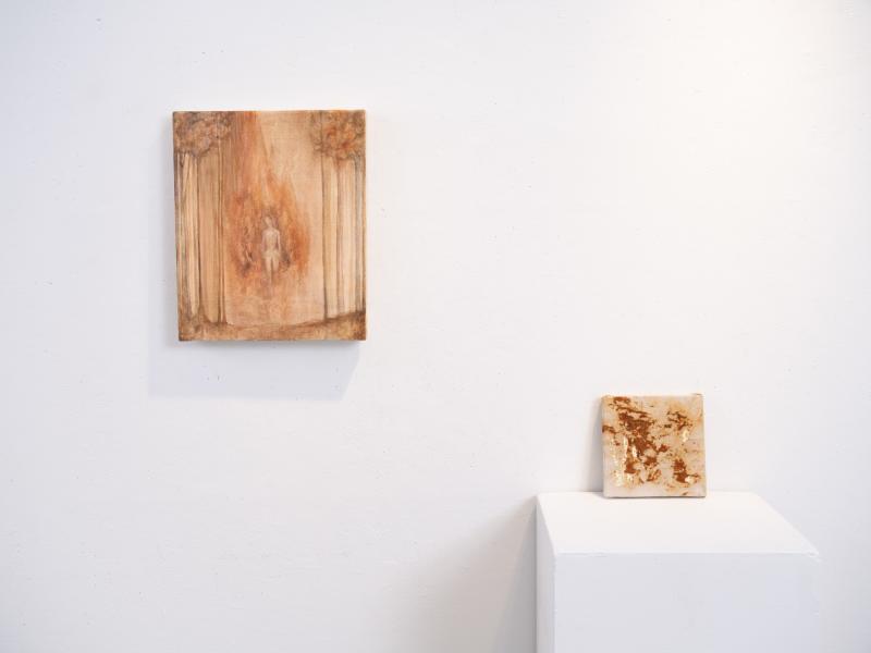 two mixed media paintings installed on a pedestal and gallery wall
