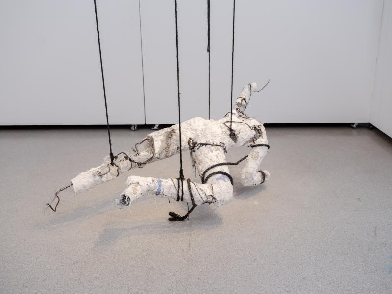 mixed media figurative sculpture suspended from a gallery ceiling