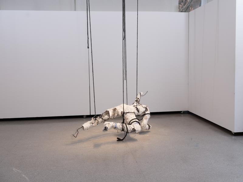 mixed media figurative sculpture suspended from a gallery ceiling