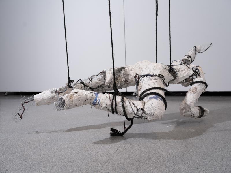 mixed media figurative sculpture suspended from a gallery ceiling