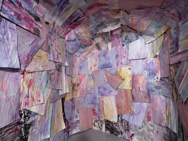 detail image of an installation using multiple works on paper installed on the walls and ceiling of a gallery