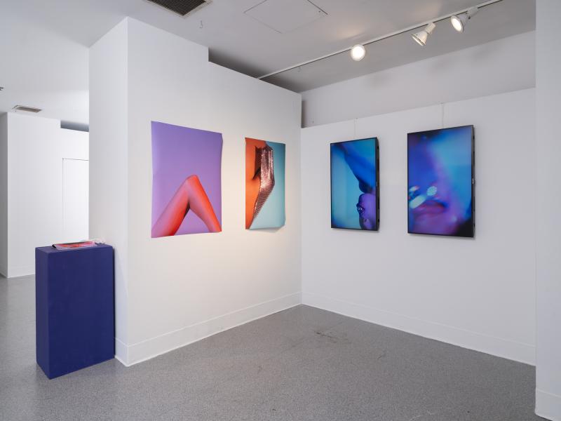 multiple photographs, digital video on monitors, and book on a pedestal