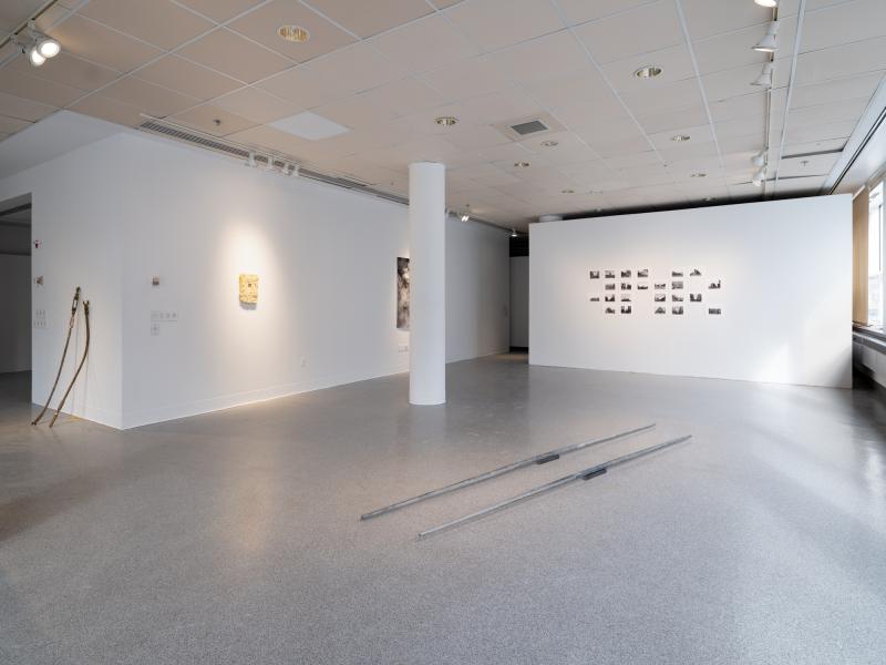 installation image with multiple sculptures, photographs, and wall pieces