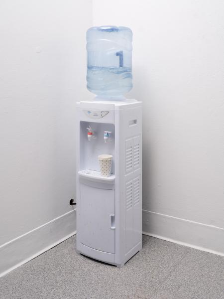 sculpture using a water cooler installed in a gallery corner