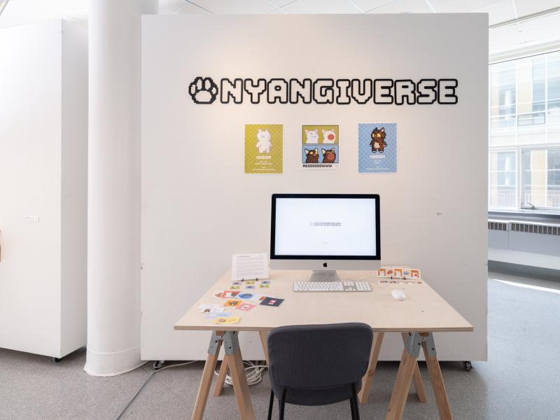 multi media installation using wall text, a monitor on a desk, and pamphlets 