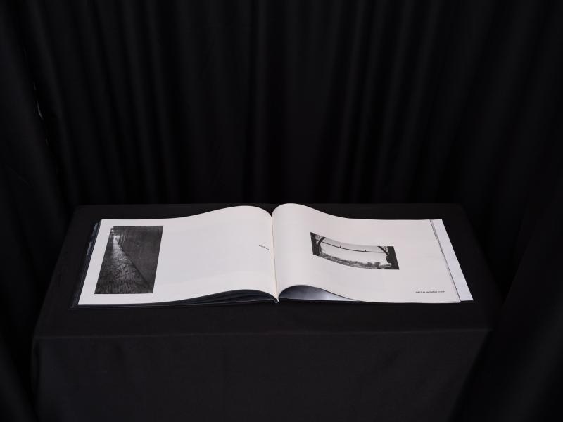 a book installed on a black pedestal in a dark space in a gallery 