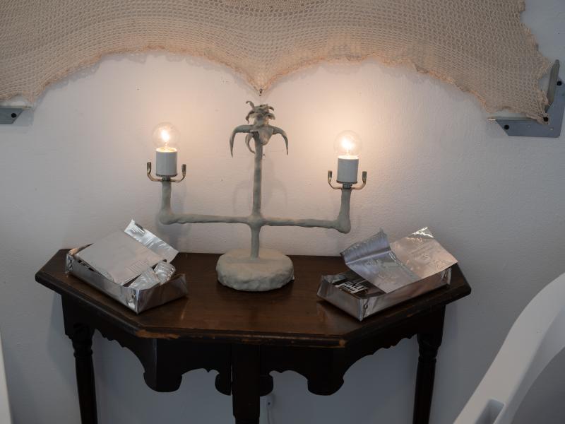 detail of a mixed media piece installed on the wall and a table