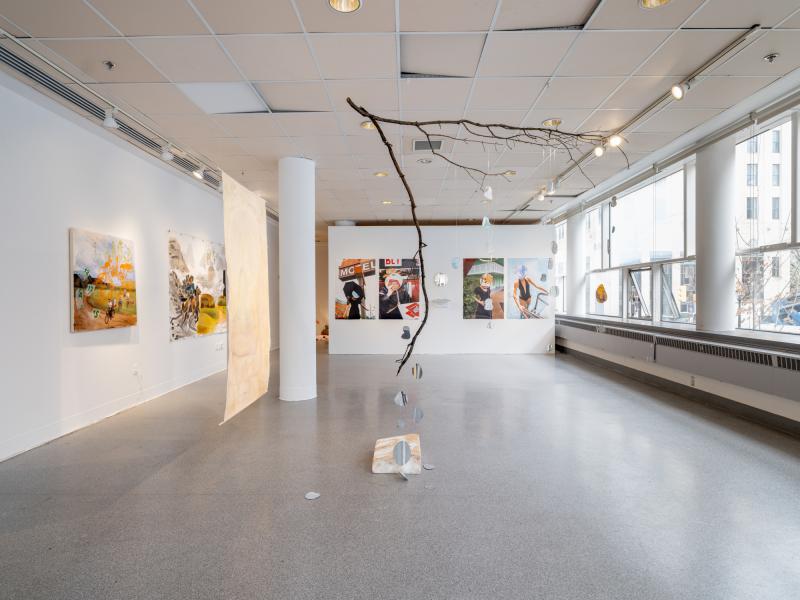 installation image of a ceiling hung sculpture, paintings, and photographs 