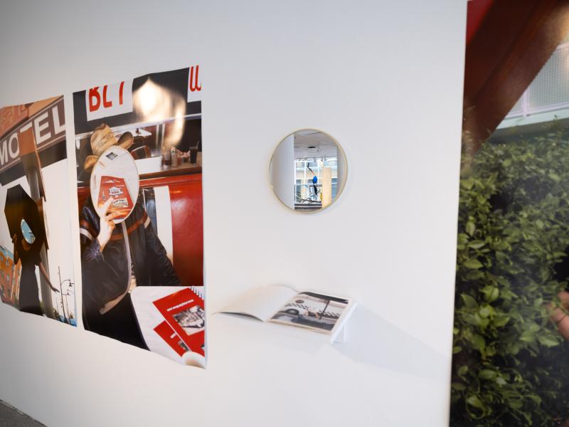 detail image of a mirror, shelf, and large photographs installed on a gallery wall