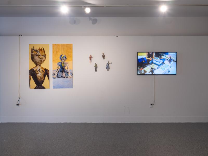 multiple photographs, digital video on monitor, and mixed media sculptures installed on a gallery wall 