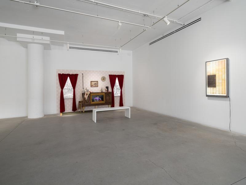 installation using a TV, curtains, and decorative objects, and a light box on the right