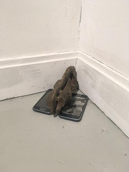 small sculpture placed in the corner using broken touchscreen cell phones and bronze