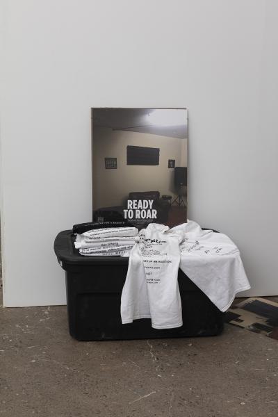 image of t-shirts and poster on a plastic bin sitting on the floor