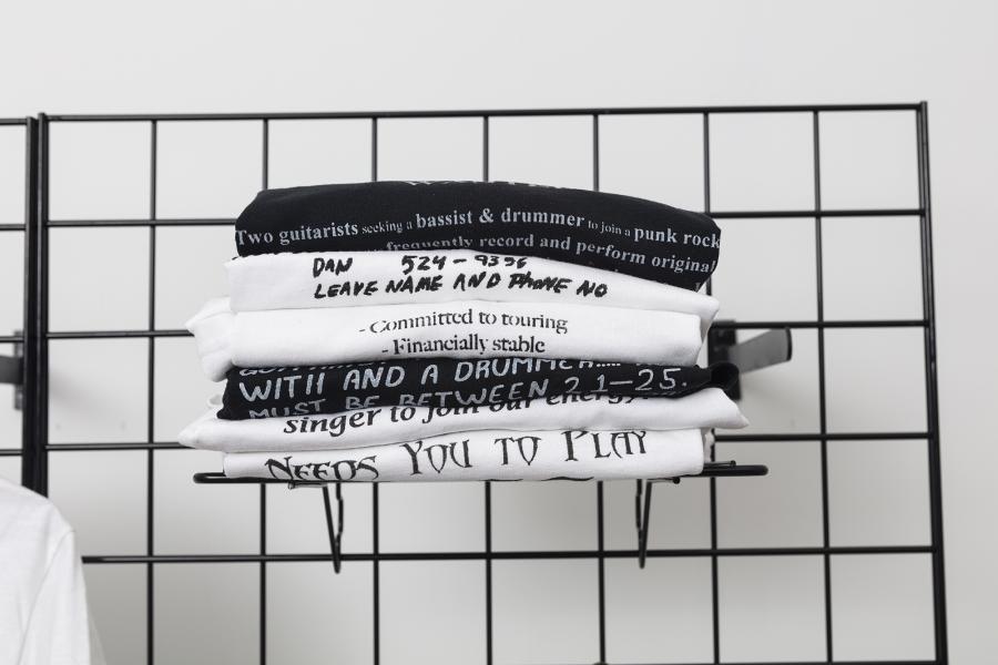 folded t-shirts on shelf mounted to black grid