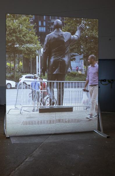 image of a large projection on a freestanding screen of the back of a bronze sculpture
