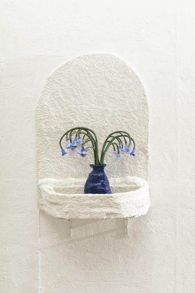 image of a wall mounted fountain with a vase and flowers