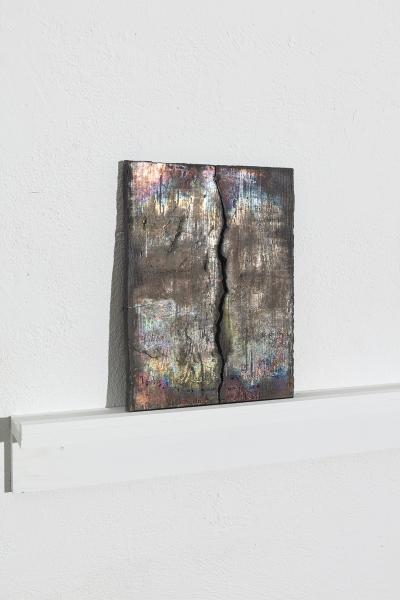 side image of a darkly glazed ceramic piece on a shelf mounted to the wall