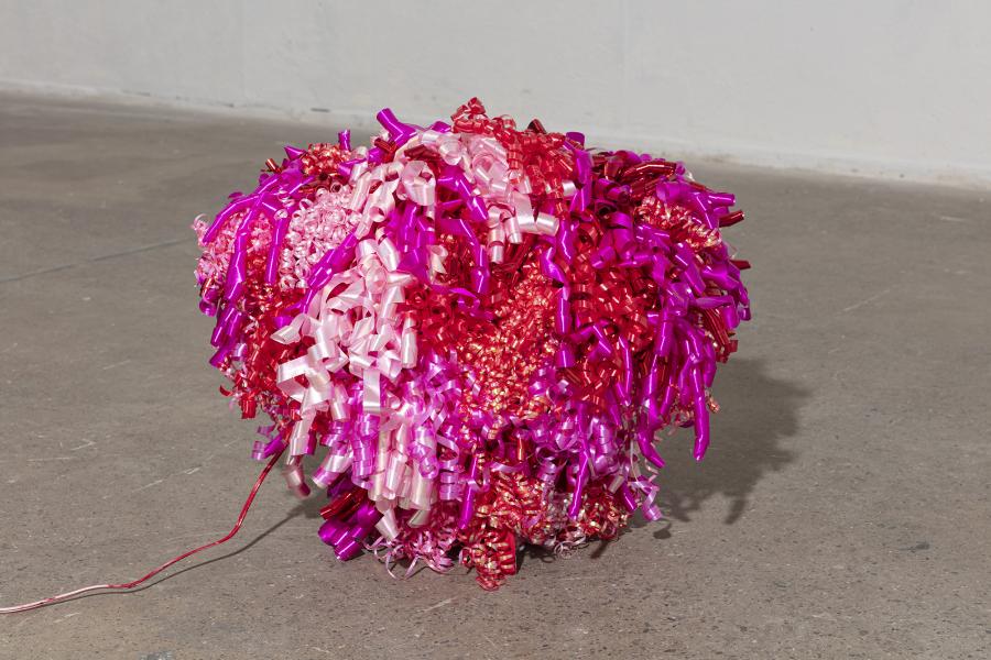 image of floor sculpture in the rough shape of a heart covered with various shades of pink curled ribbon