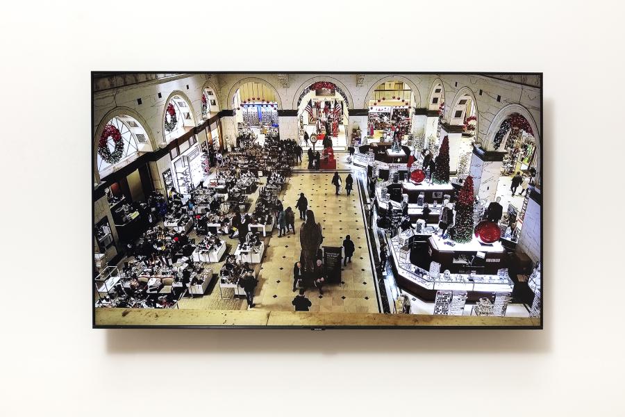 image of monitor displaying a grand interior filled with people from above
