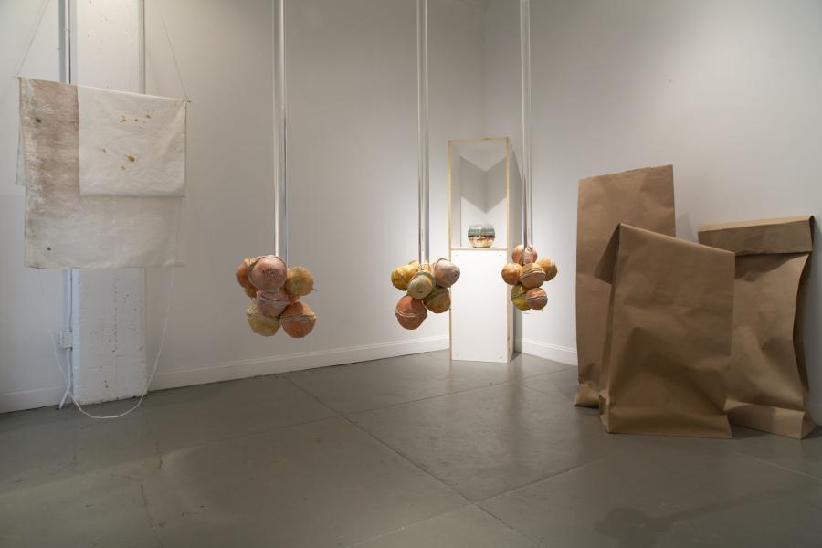 multiple pieces hanging from the ceiling with large paper bag sculptures on the right 