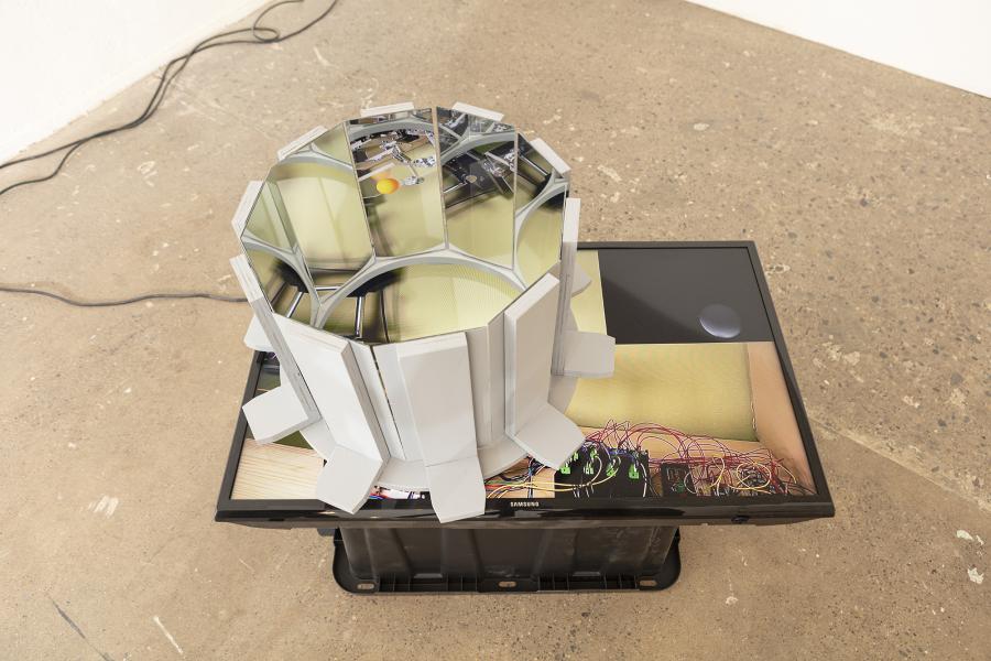 image of a floor sculpture with monitor, mirrors, and plastic bin